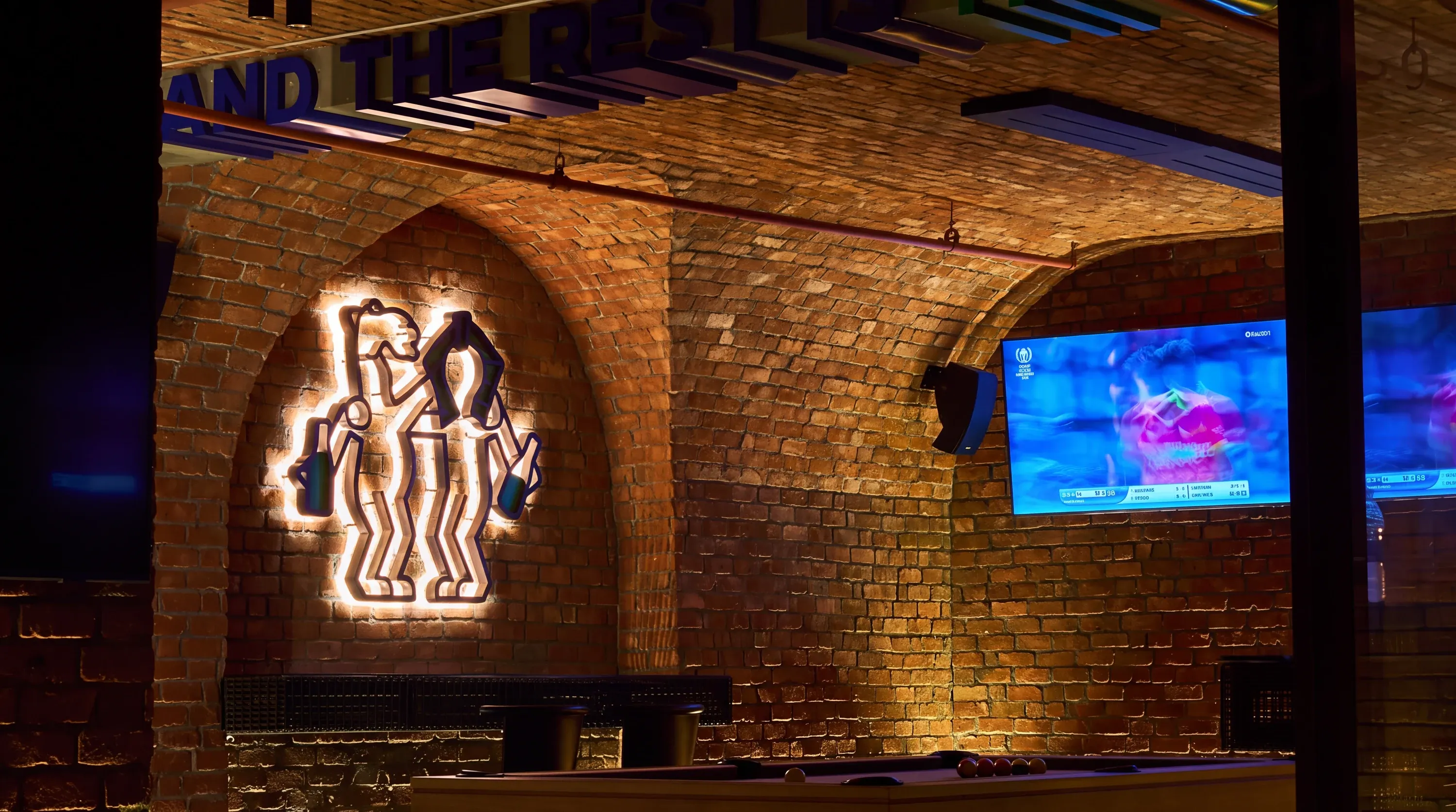 Lit camel logo on an arched brick wall above a pool table