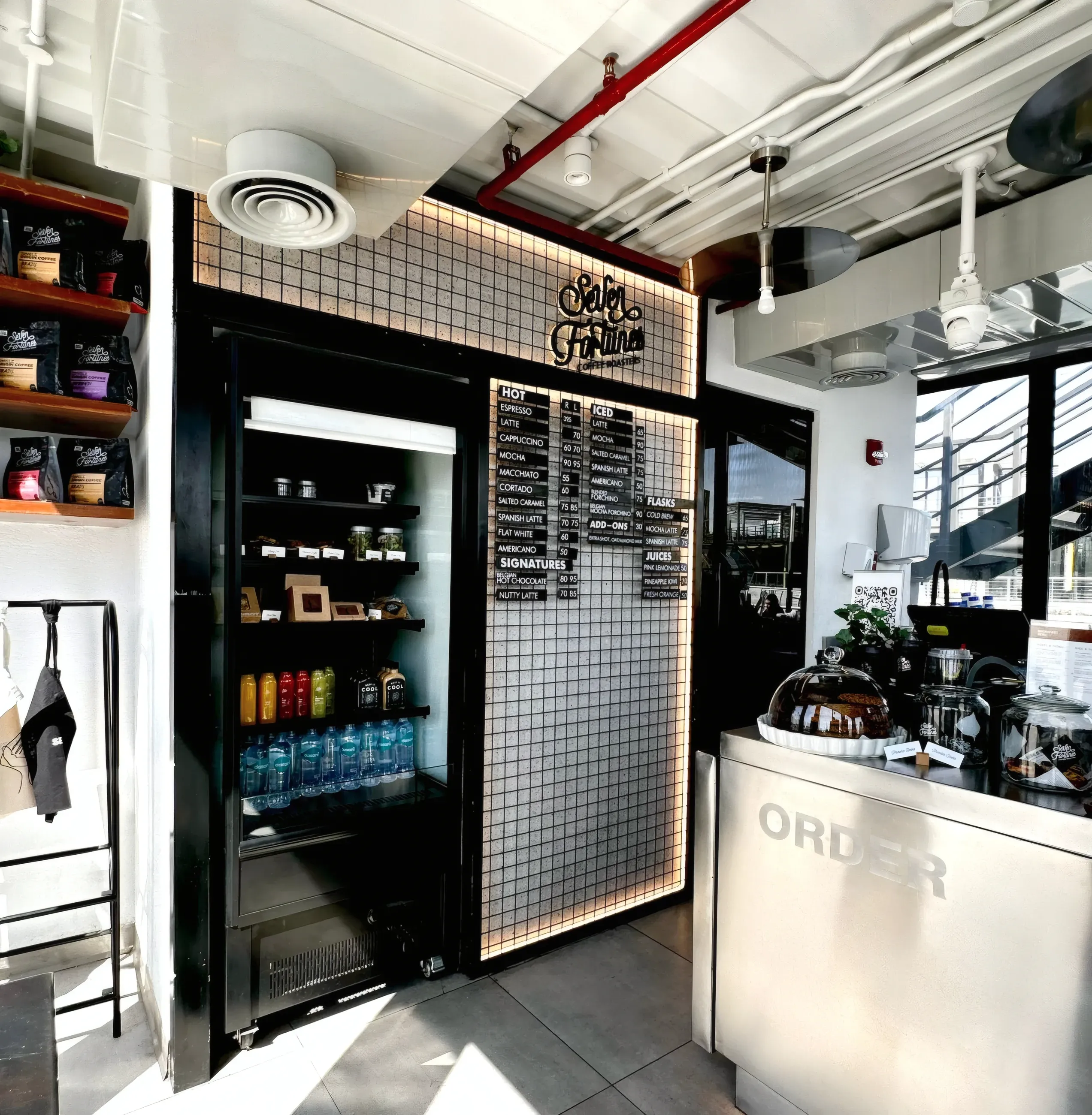 Coffee bar corner with black steel frame, mesh menu panel and white order counter