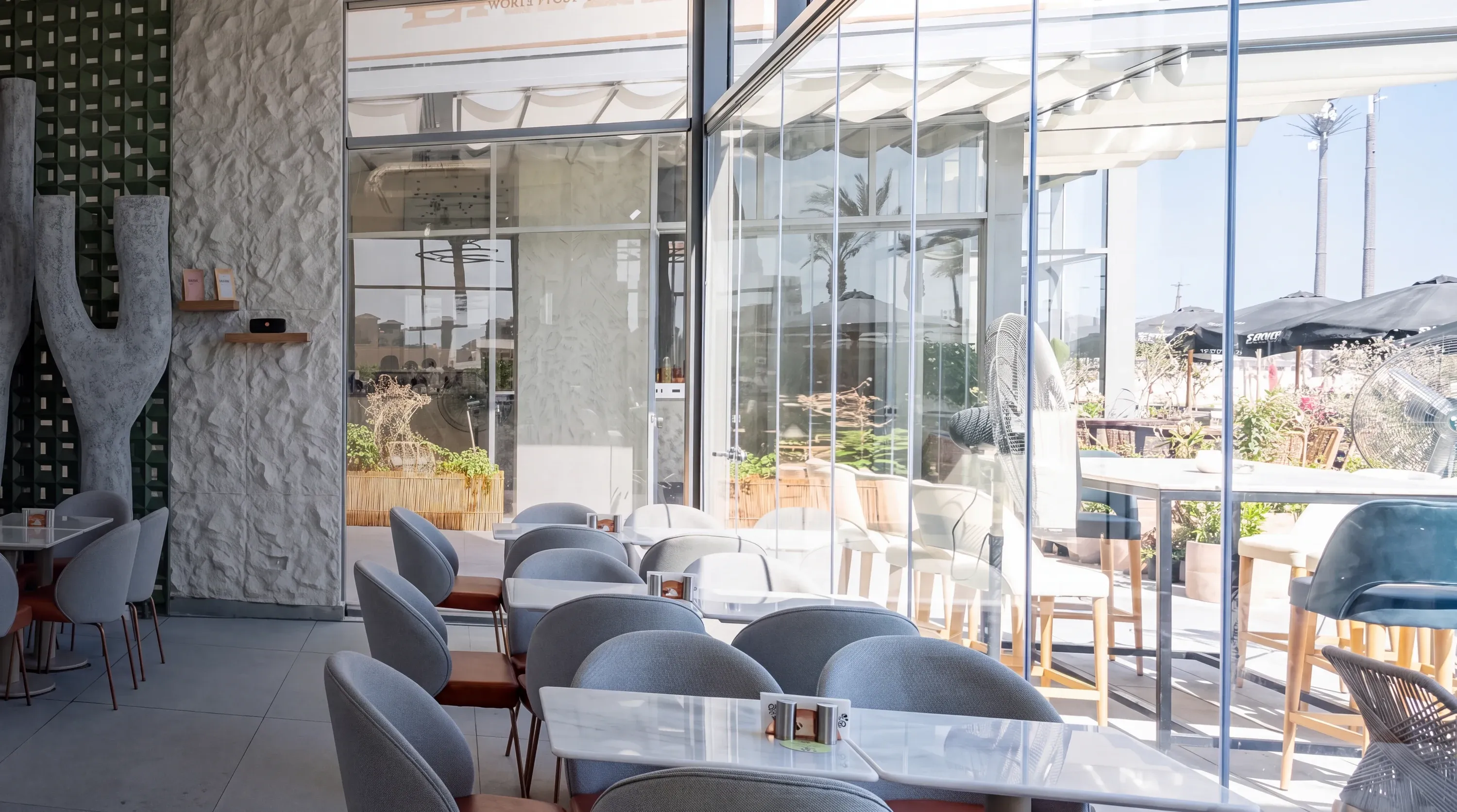 Coffee shop with grey chairs, textured white wall and glazed frontage
