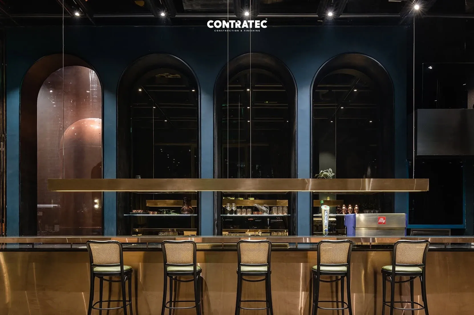 Brass-fronted bar with five stools beneath blue arched niches