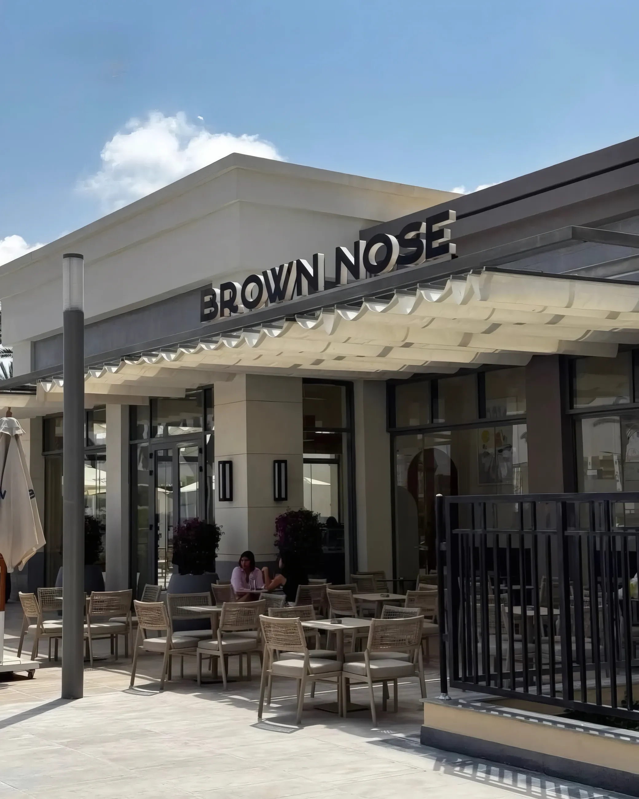 Brown Nose entrance under a canopy with outdoor tables