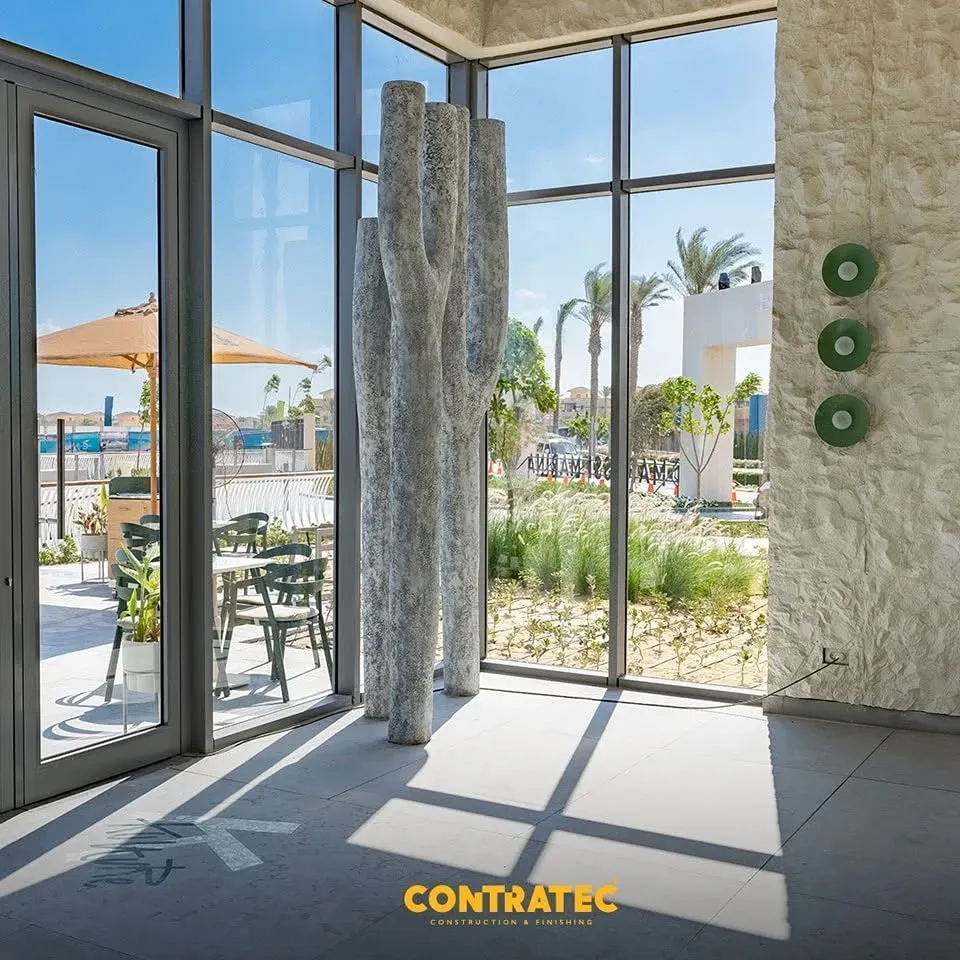 Sculpted white pillar beside glass doors opening onto a sunlit terrace