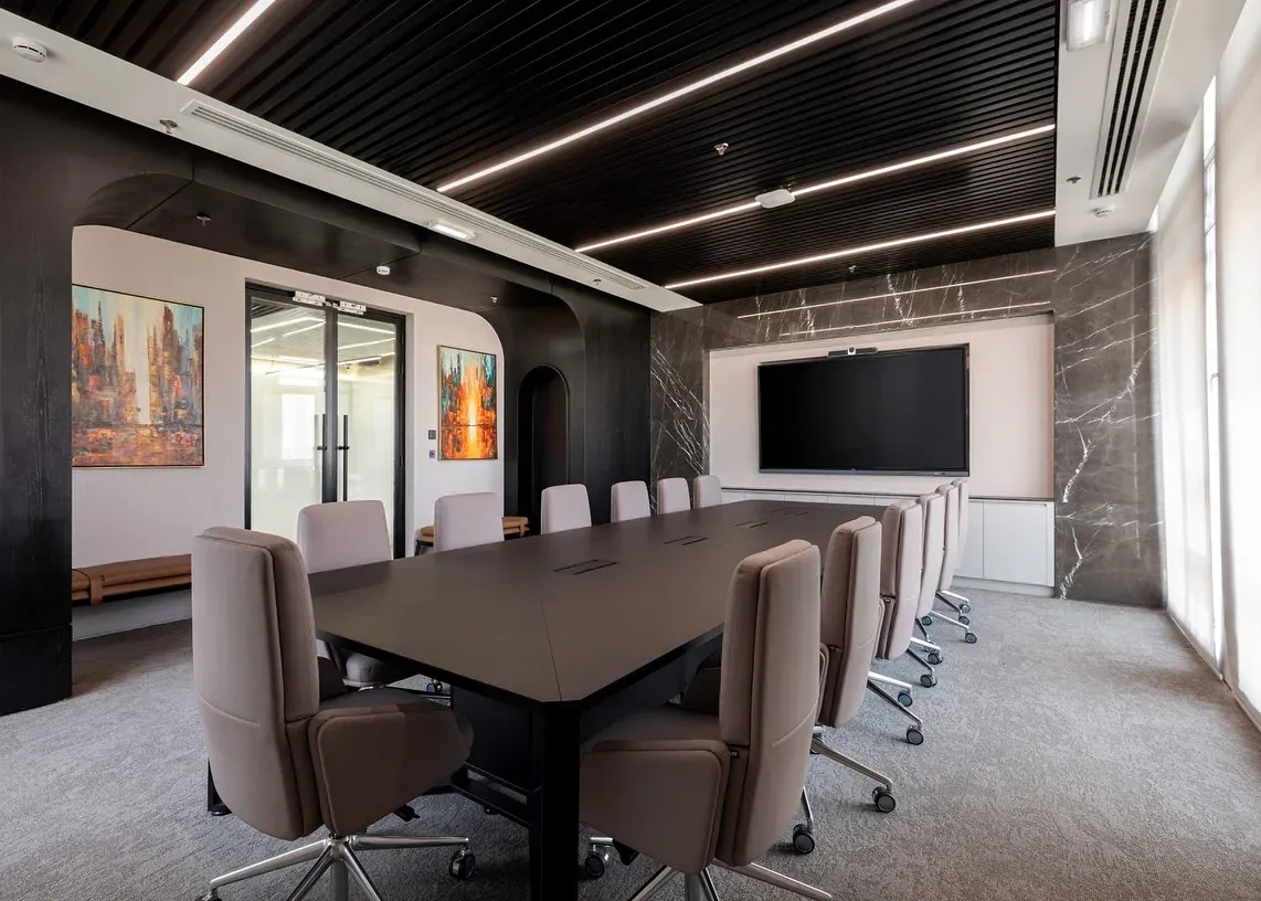Boardroom with long dark table, grey chairs and a marble feature wall