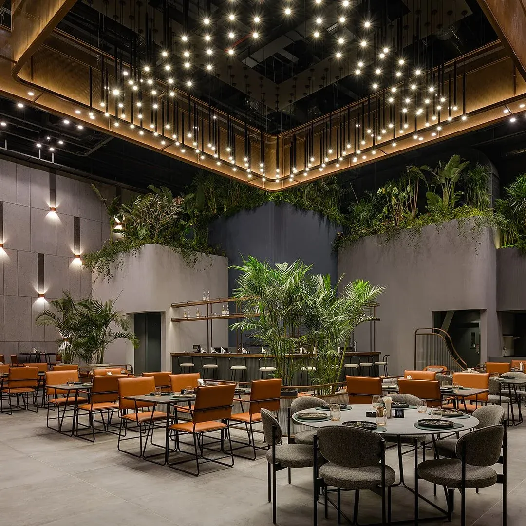 Orange chairs and tables beneath the canopy of ceiling lights