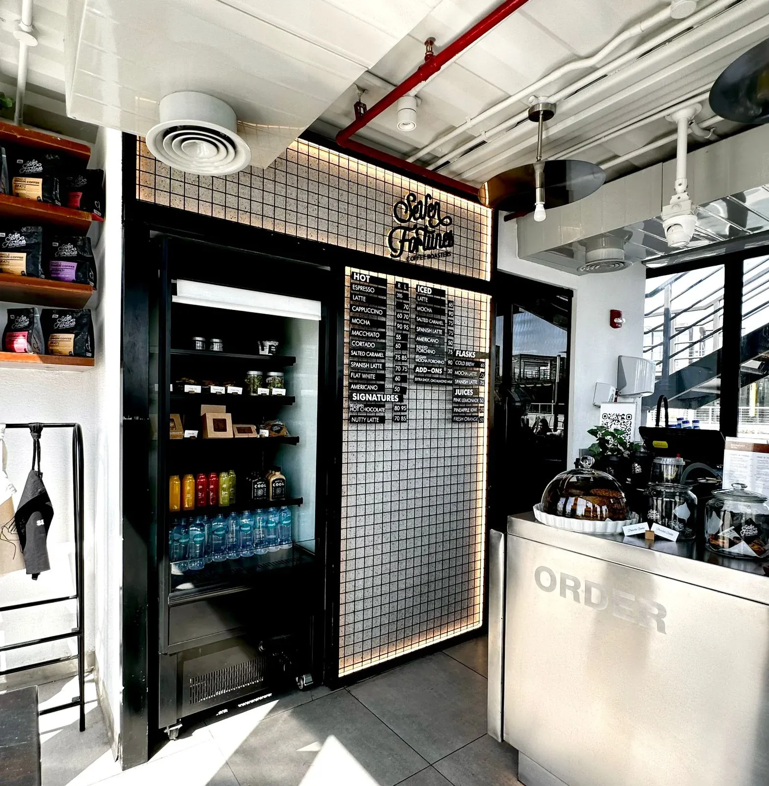 Order counter and drinks shelves beside the mesh menu board