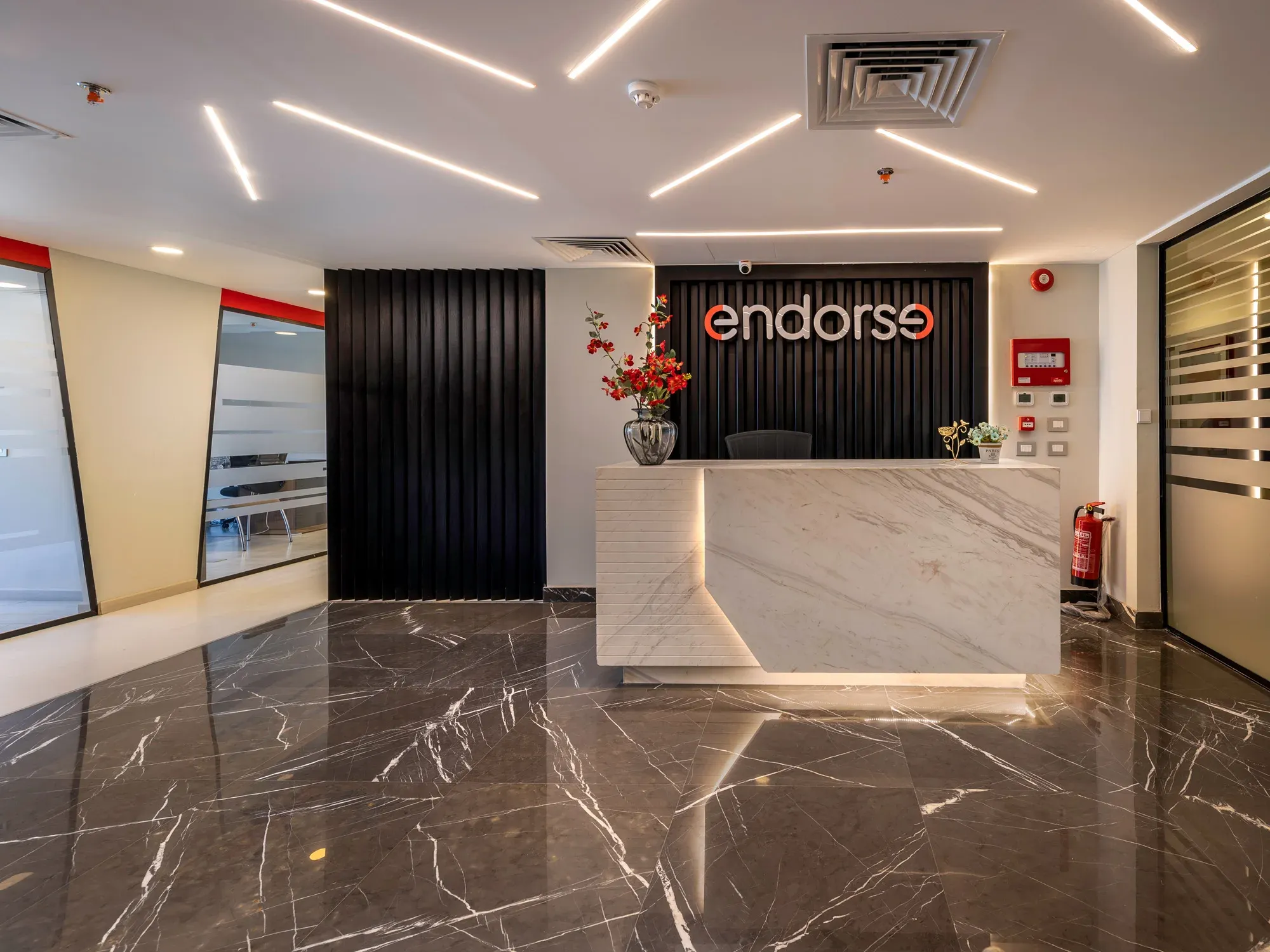 White marble reception desk under angled ceiling light lines, Endorse logo behind