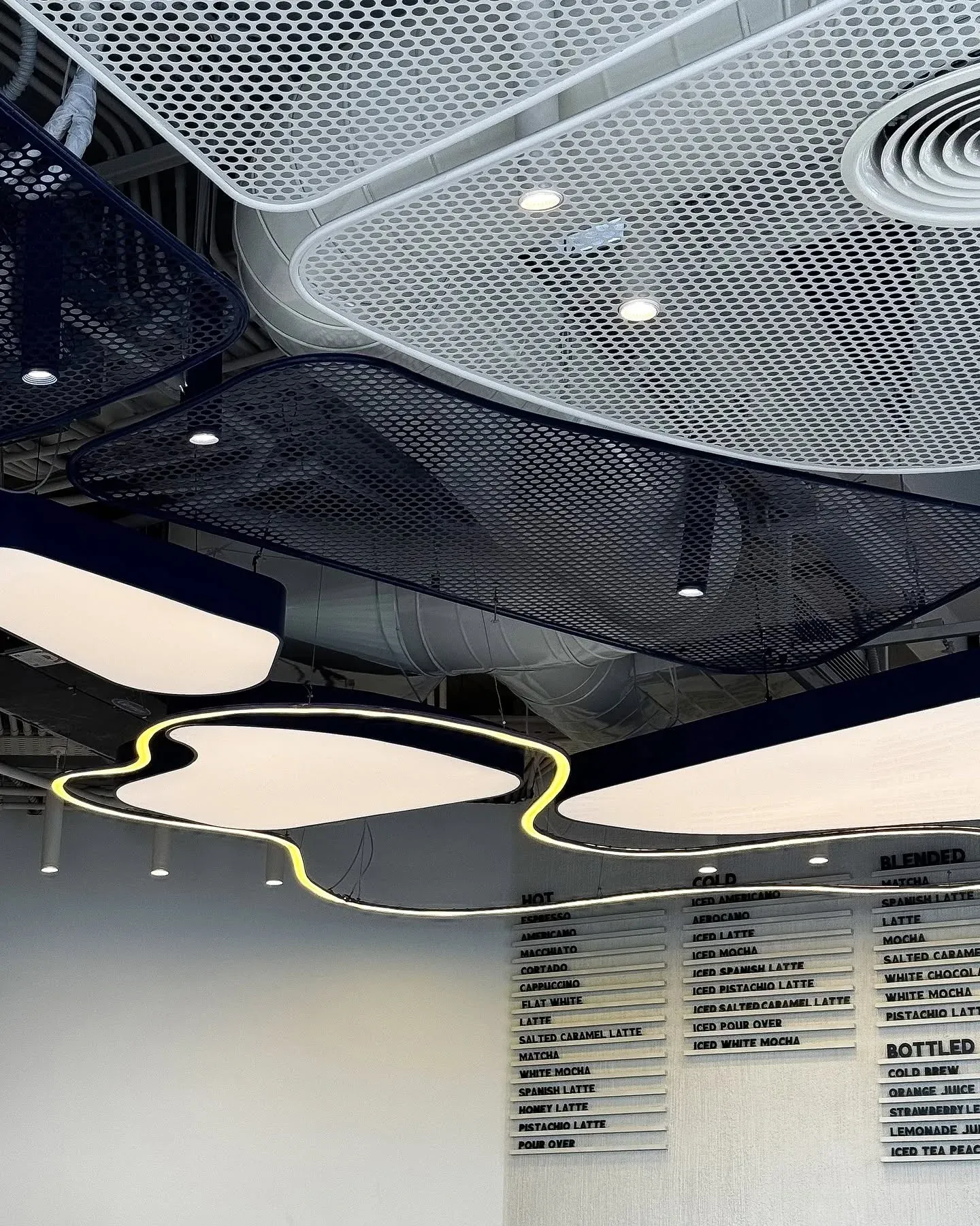 Dark mesh ceiling with pale light shapes above a menu board