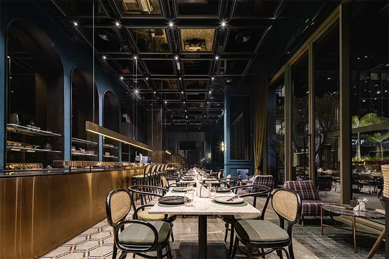 Long dining room with brass bar, coffered ceiling and cane chairs