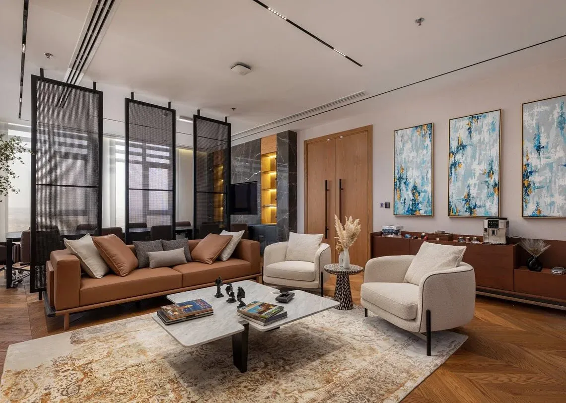 Office lounge with tan leather sofa, cream chairs and blue abstract paintings
