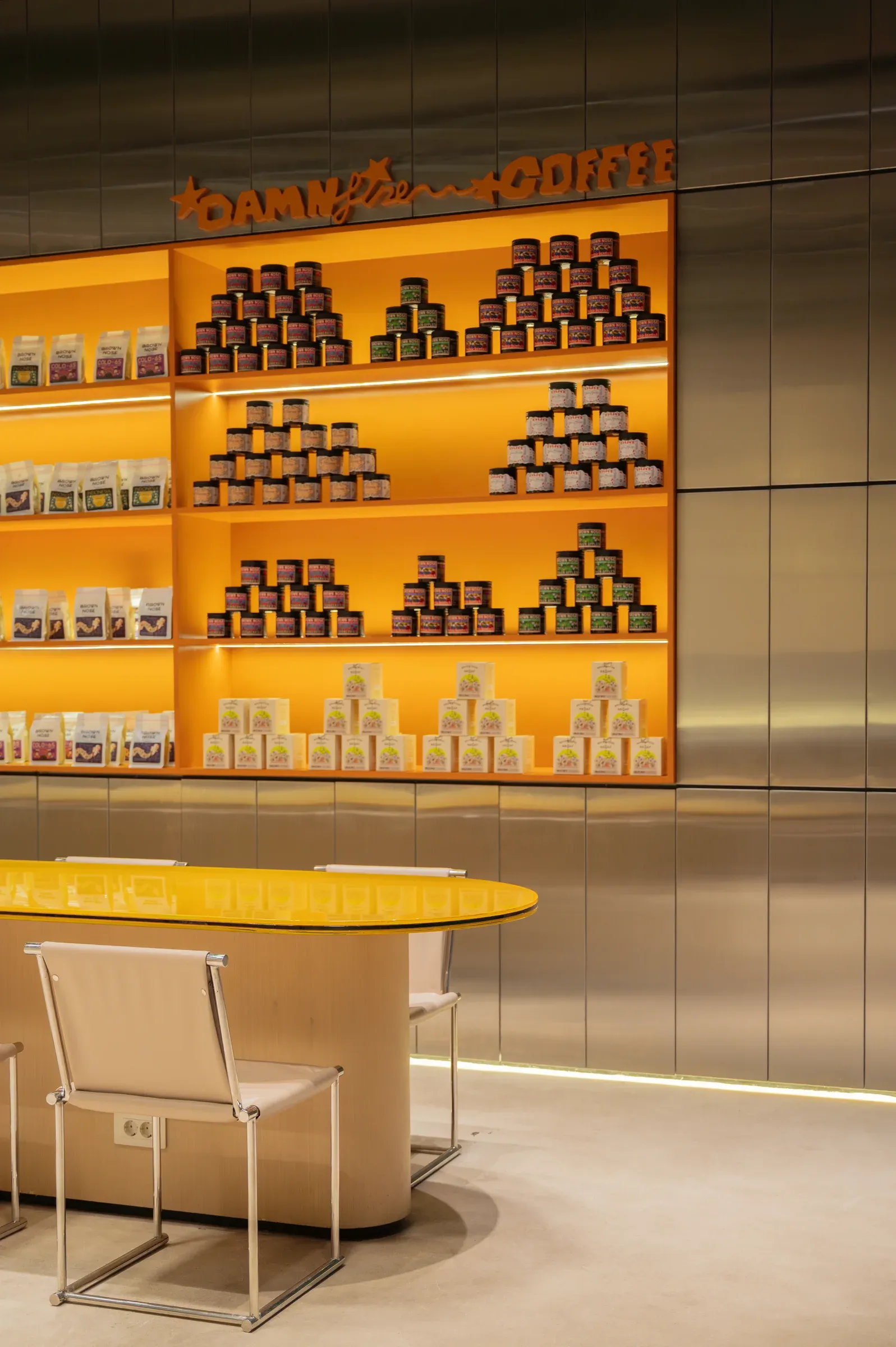 Coffee tins stacked on orange shelves above a yellow counter