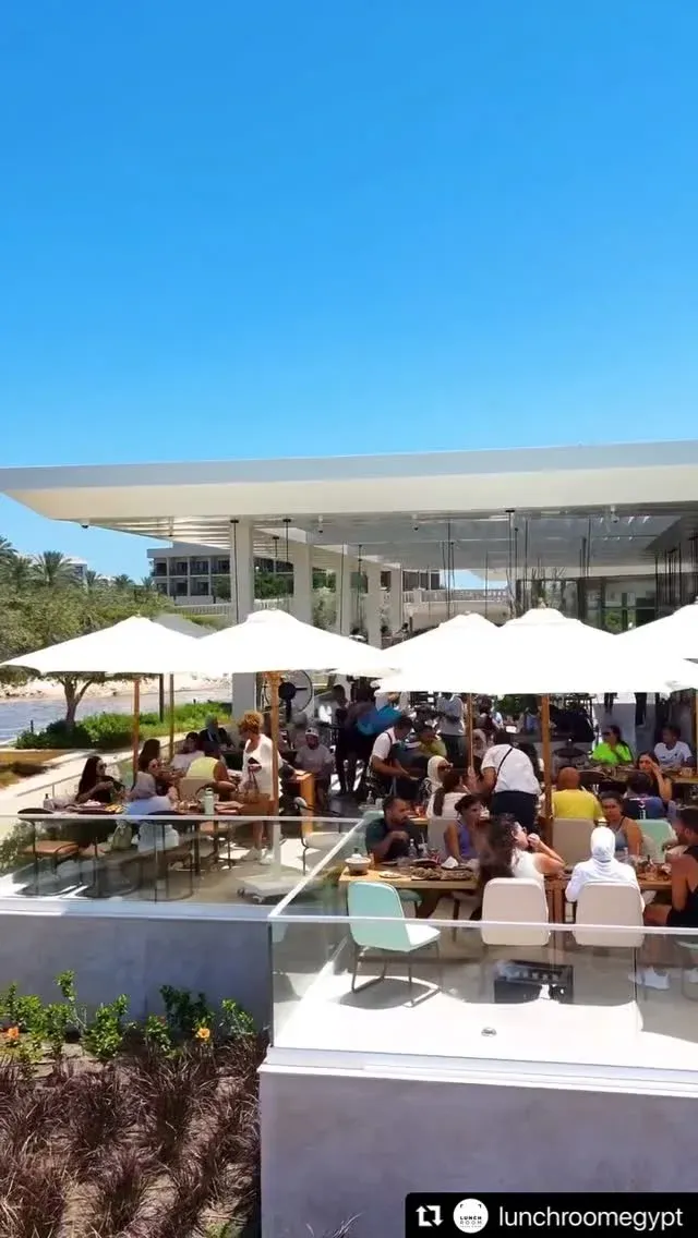 Diners under white shade umbrellas on a sunny terrace