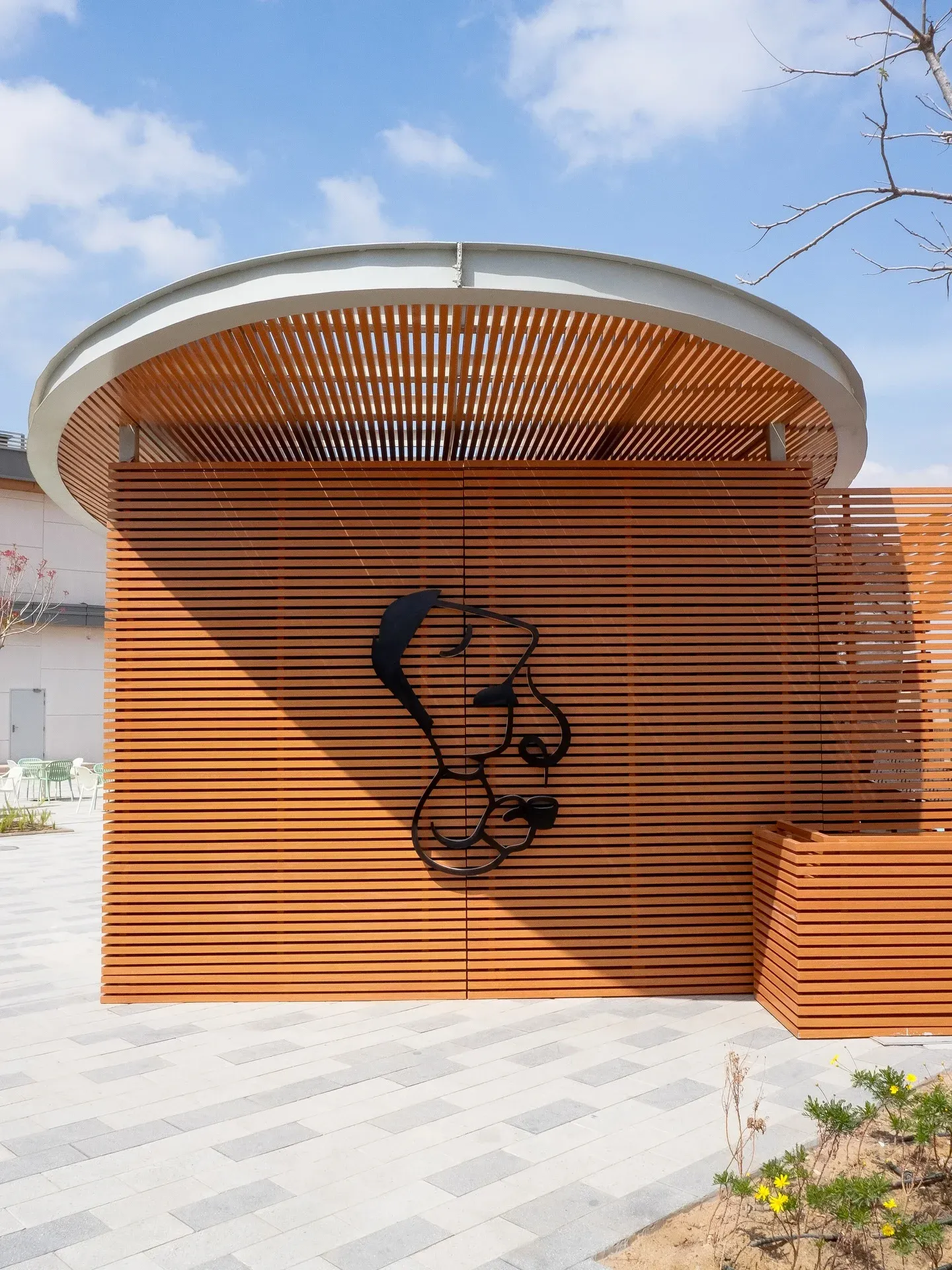 Timber slat wall with black logo under the curved kiosk roof