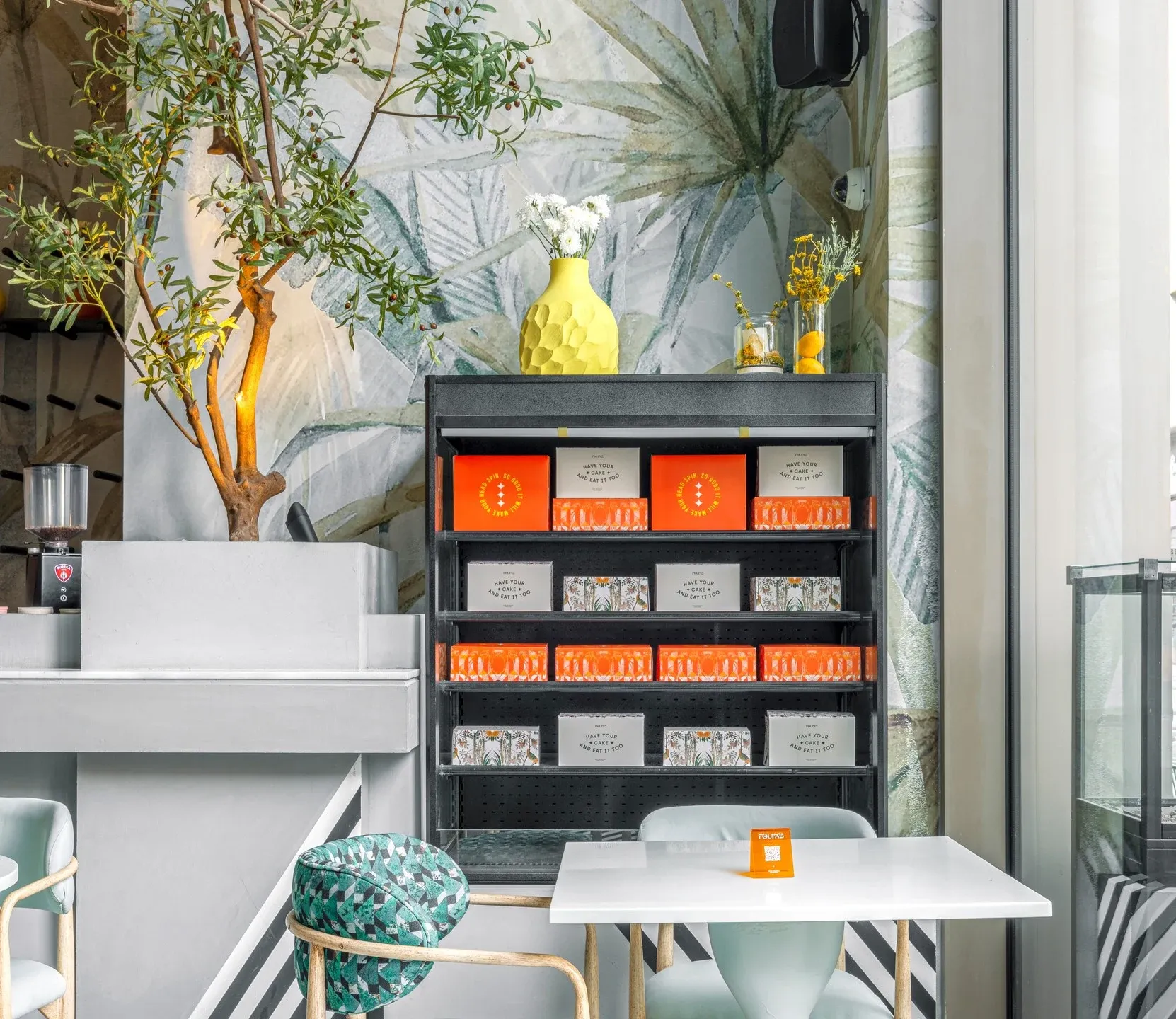 Counter and black shelving with orange boxes beside leafy wallpaper