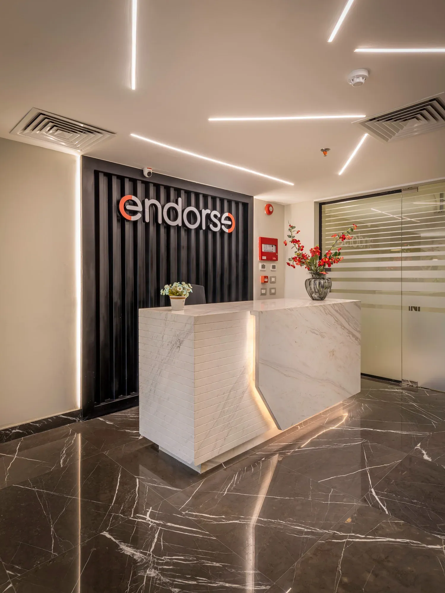 Reception desk with a lit seam against a black fluted wall