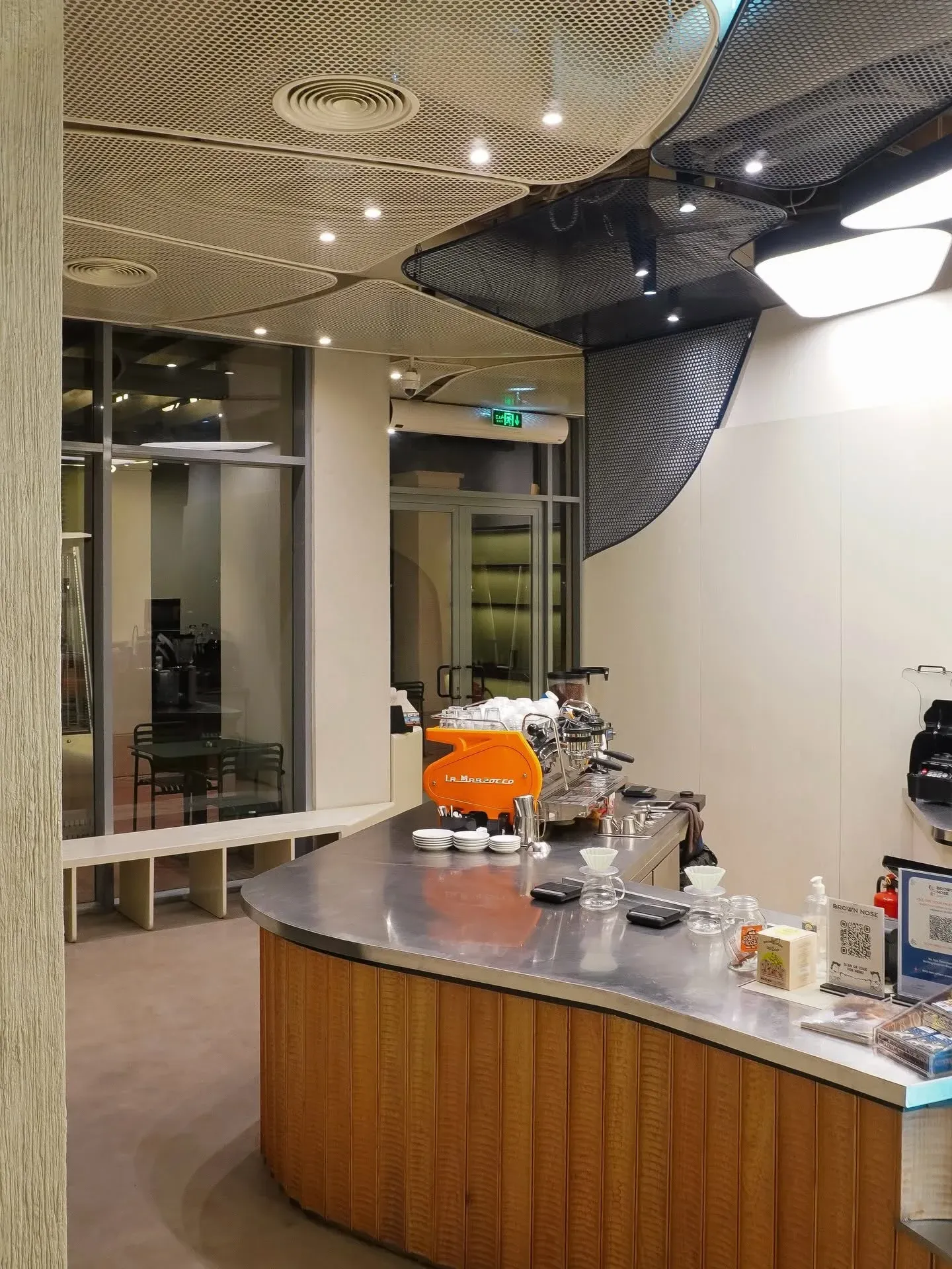 Timber-clad curved counter with steel top beside the glazed entrance