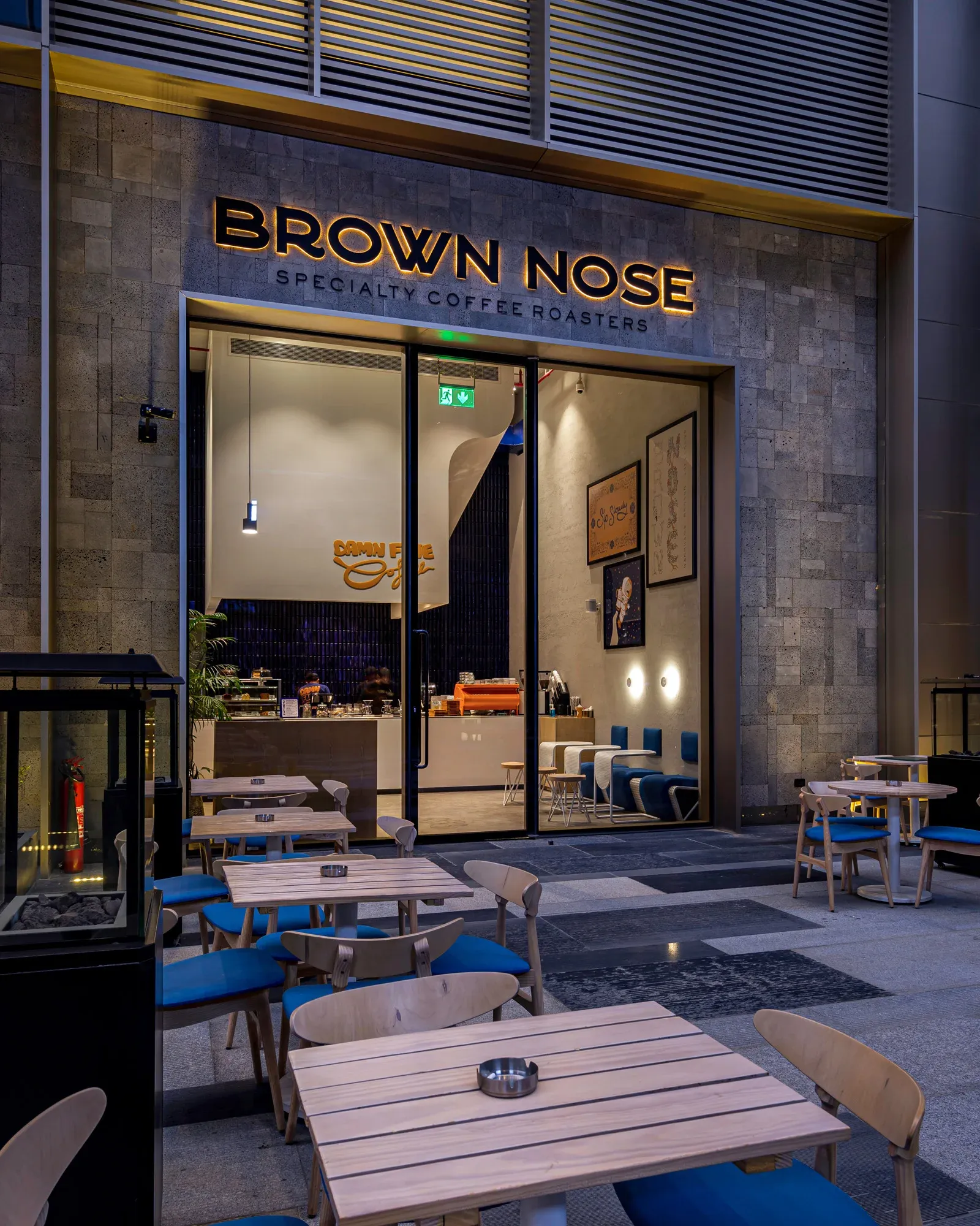 Brown Nose storefront with outdoor timber tables and blue chairs