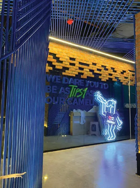 Blue steel-slat partition beside a glass wall with neon lettering