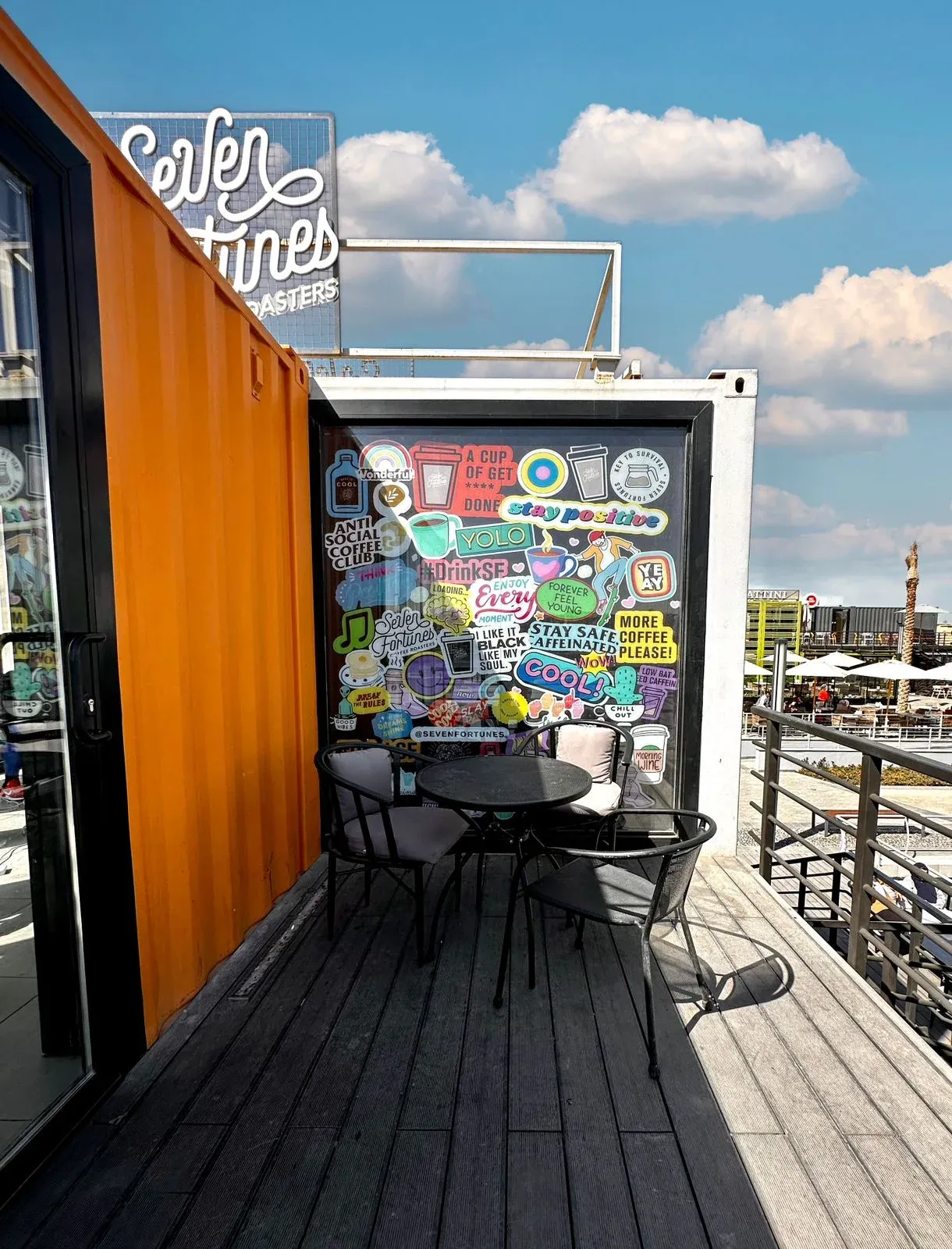 Orange container side with a sticker-covered wall and balcony seating