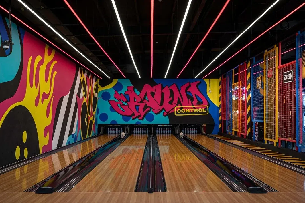 Bowling lanes with a graffiti mural at the far end, light lines above