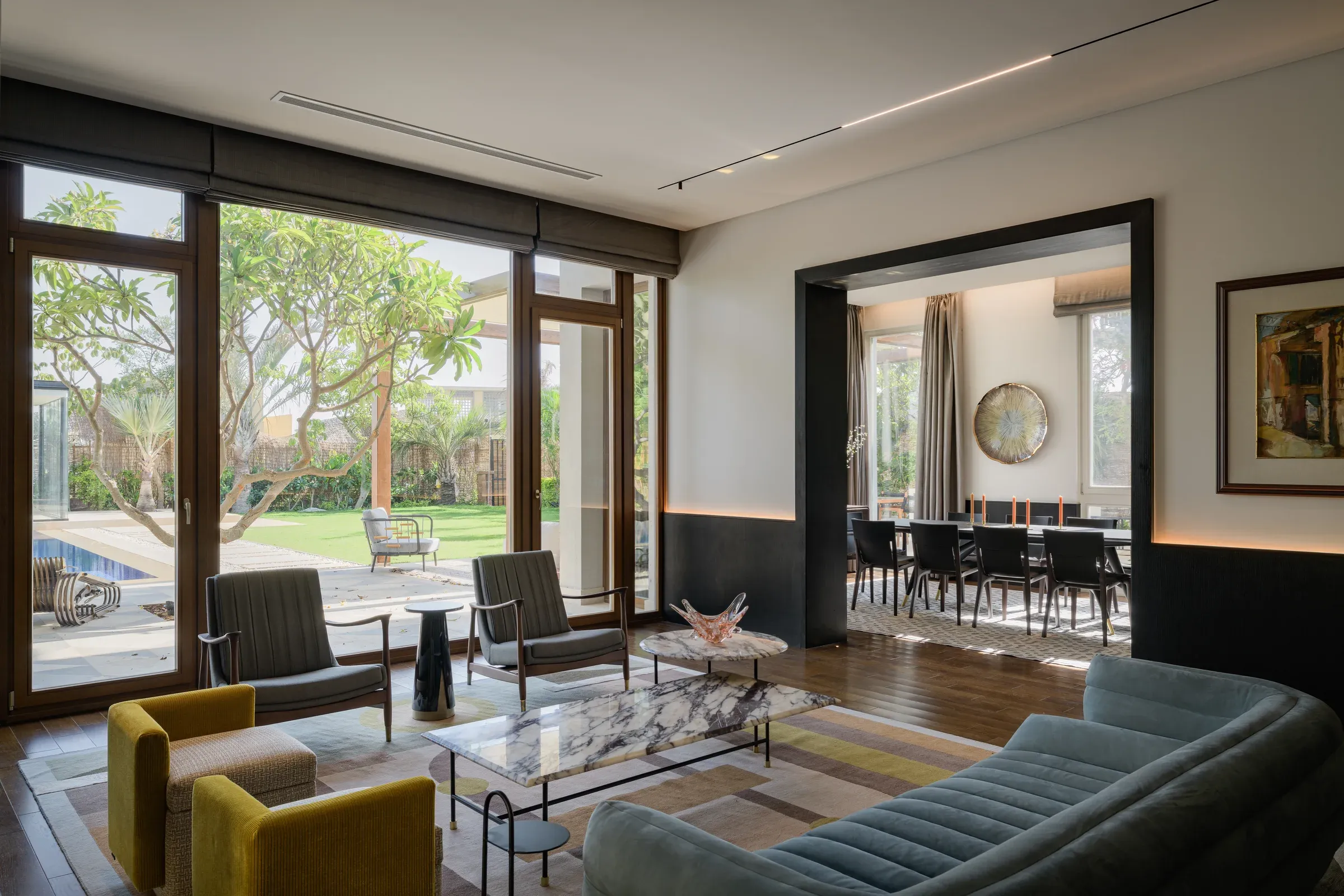Living room with blue armchairs and a dining table visible through the opening