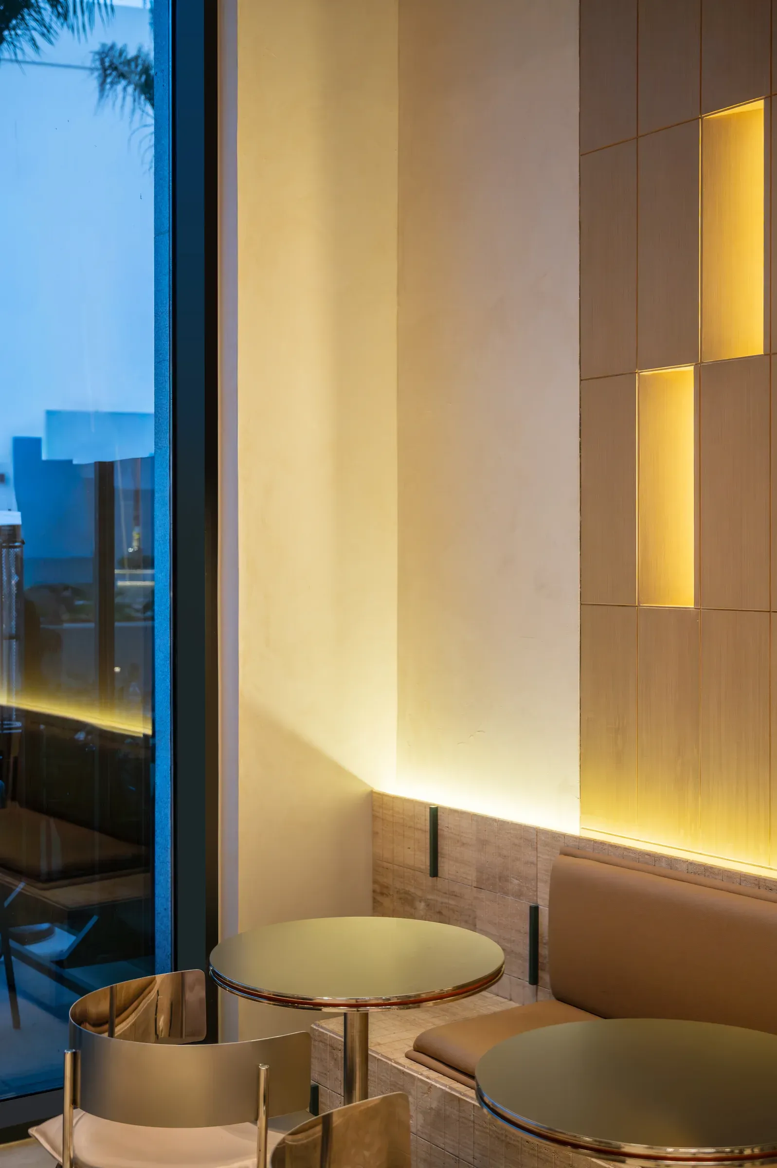 Window corner with lit vertical slots in the wall and a round table