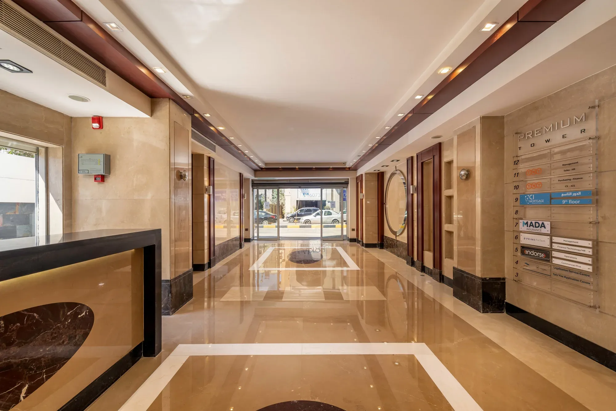 Lobby corridor with black-edged front desk and glass door at the far end