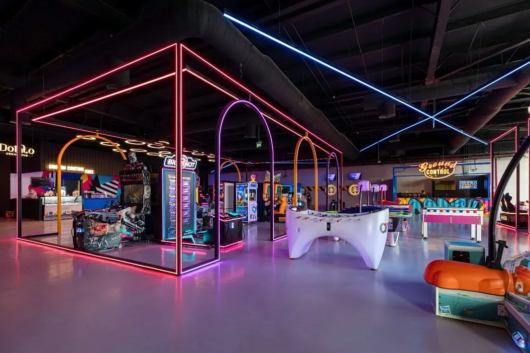Neon-framed arcade zone with air hockey tables