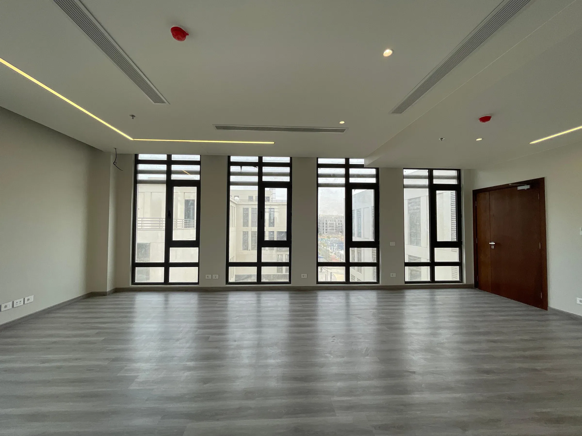 Row of four tall windows and a dark timber door on the far wall