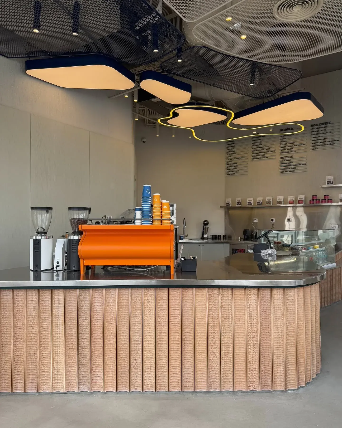 Ribbed timber counter with orange espresso machine and ceiling light pods