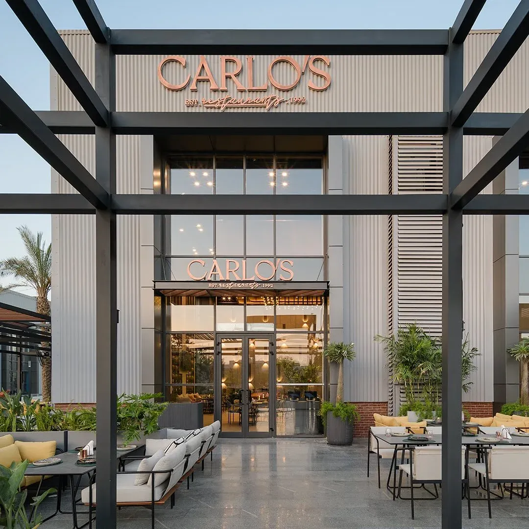 Steel pergola framing the Carlo's entrance and terrace seating