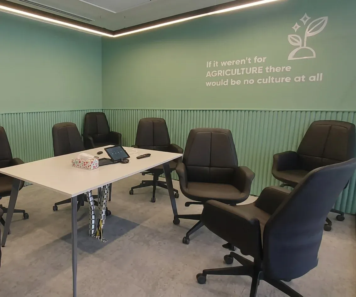 Meeting room with mint green wall graphic, black chairs and white table