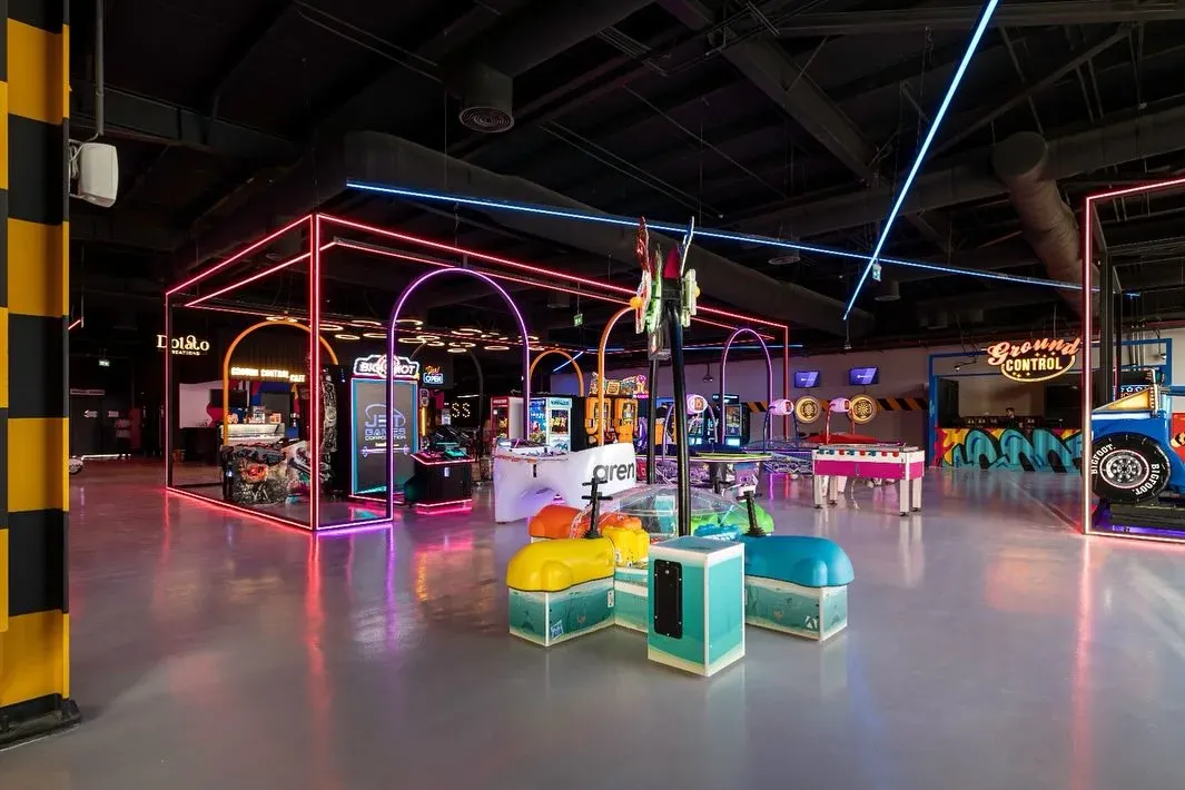 Arcade floor with neon frames, a yellow column and children's rides