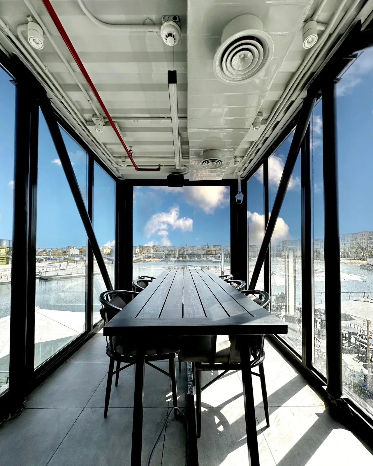 Long dark table facing the marina through full-height glazing