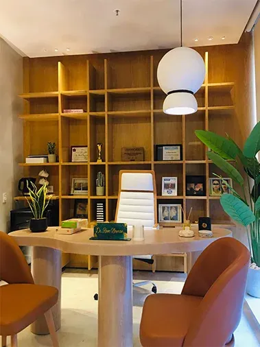 Doctor's office with timber shelving, round desk and orange chairs