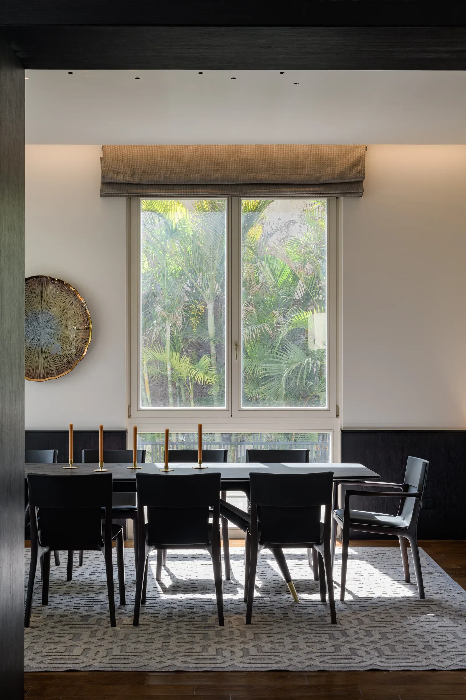 Black dining chairs around a long table in front of a window