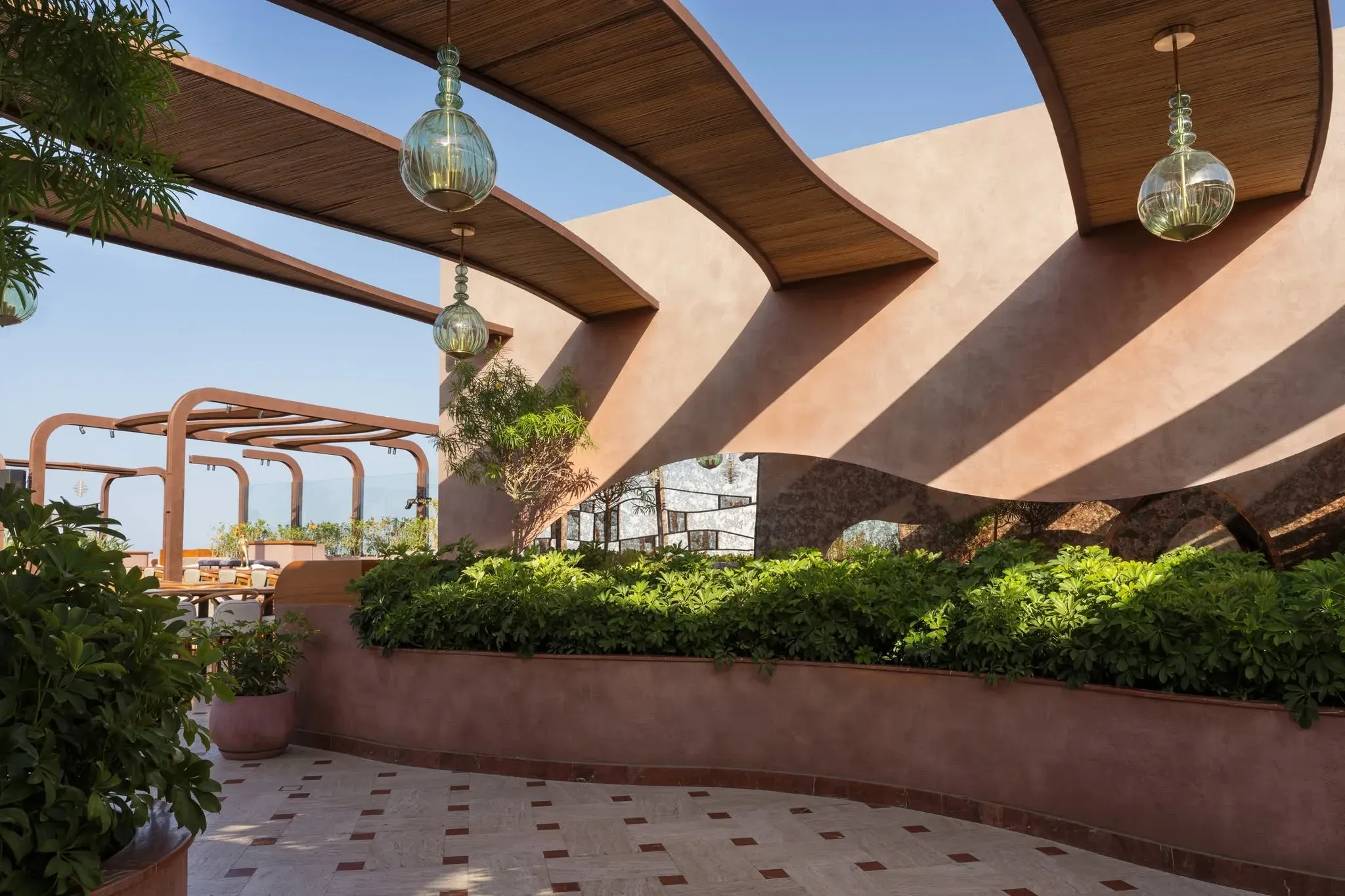 Curved terracotta walls and timber canopy with hanging glass lanterns