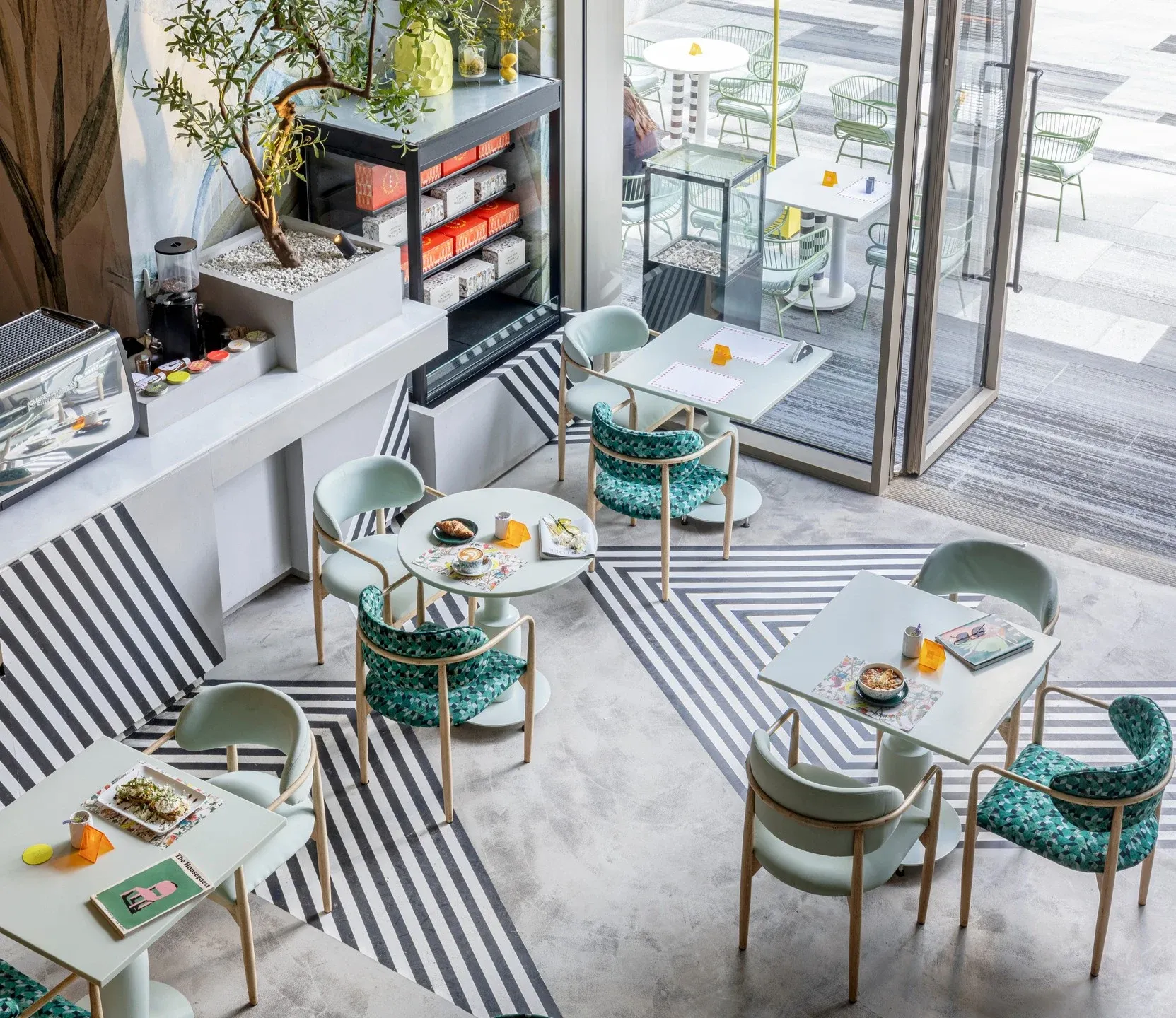 Overhead view of tables and teal chairs on a striped black and white floor