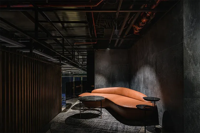 Orange curved sofa against a dark stone wall in a lounge corner