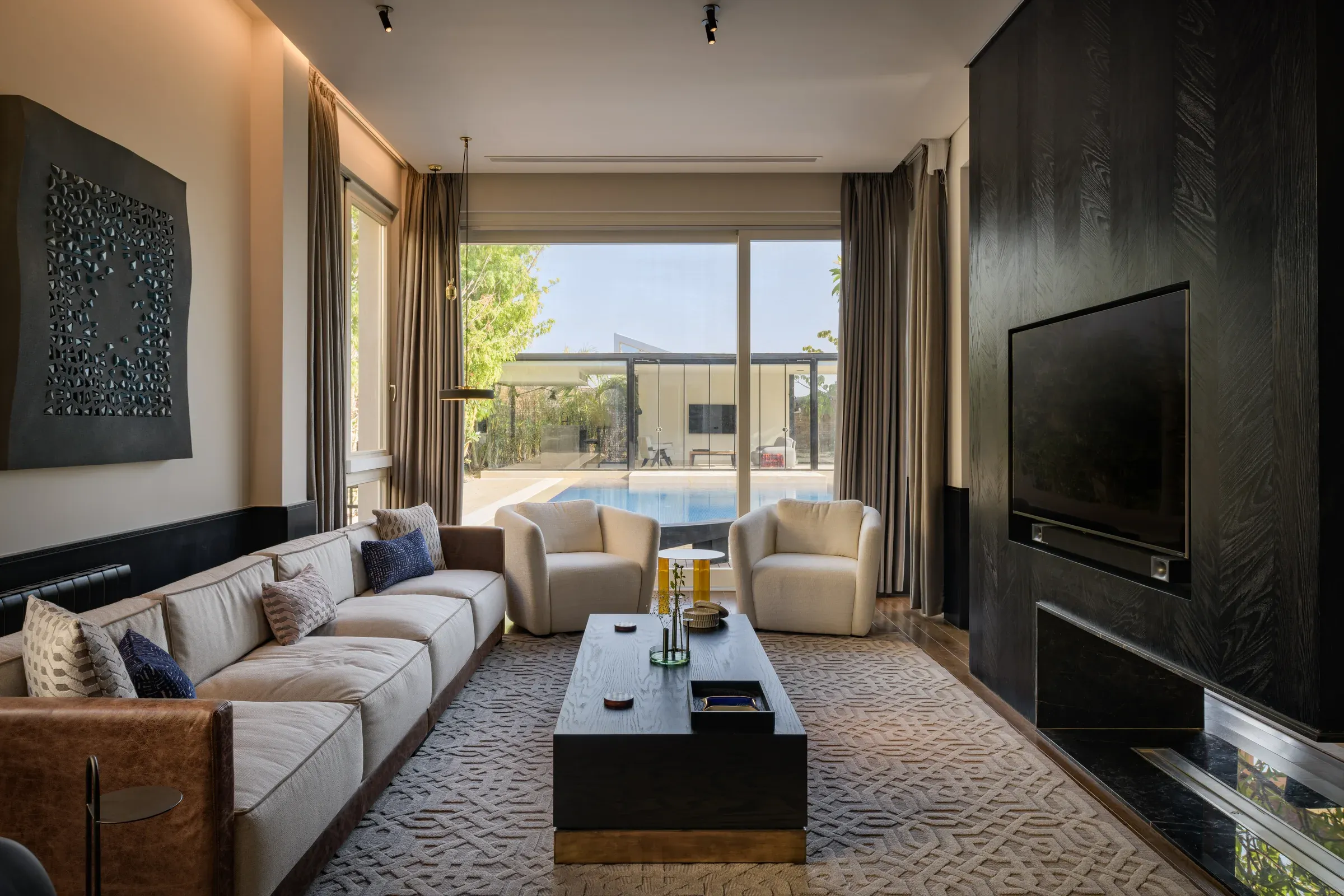 Cream sofa and black coffee table beside a dark timber wall with television