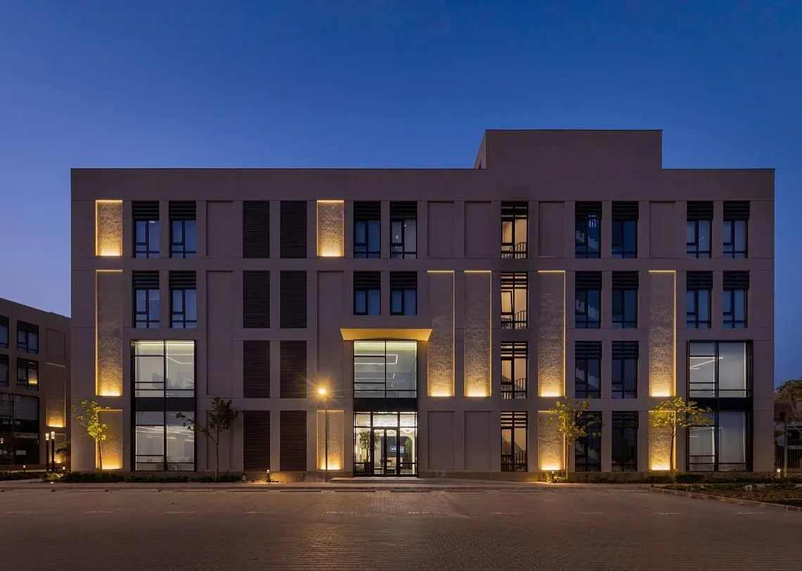 Four-storey office building at dusk with warm uplighting