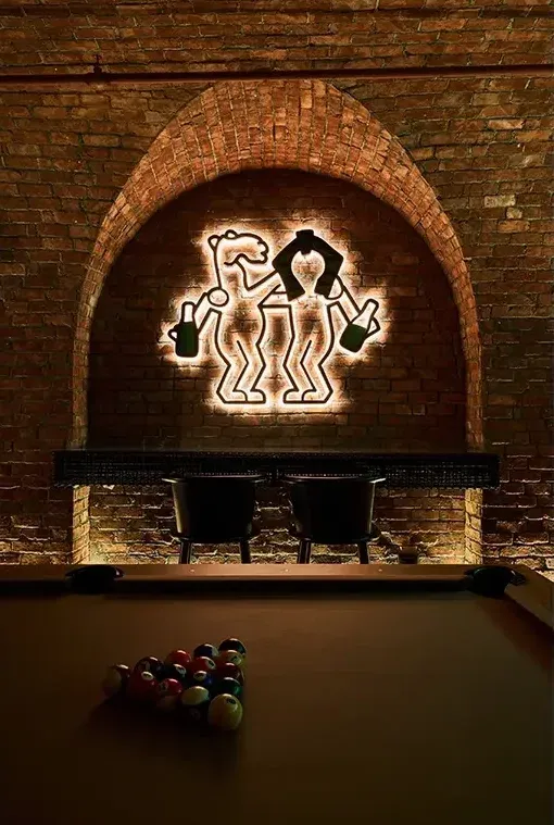 Illuminated camel logo in a brick arch above racked pool balls