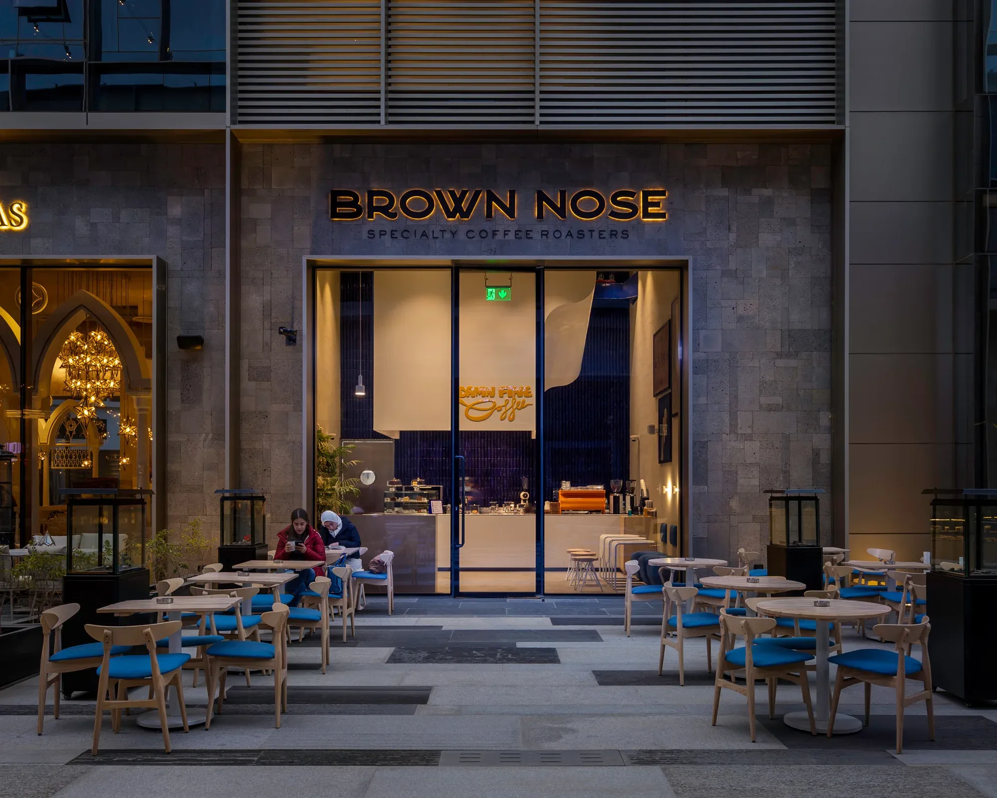 Storefront beside an arched neighbour, diners at outdoor tables