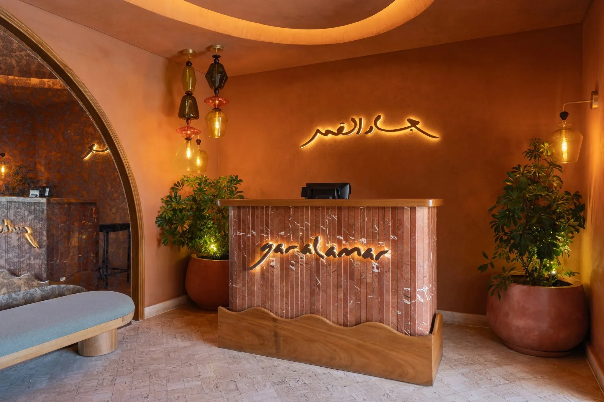 Host stand with illuminated sign against an arched terracotta wall