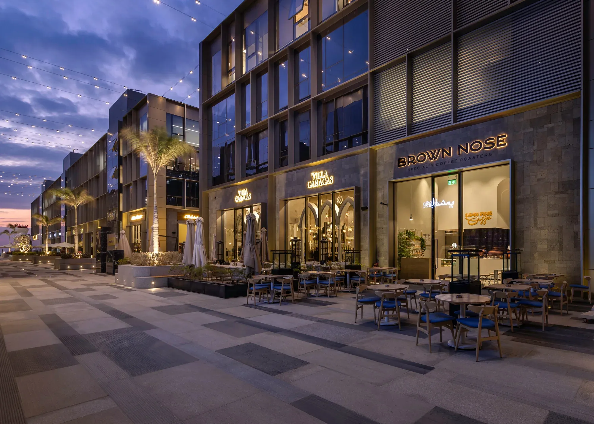 Dusk view of the shopfront row with outdoor seating along the walkway