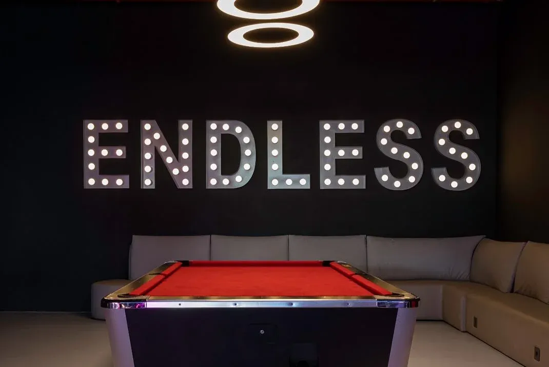 Pool table with red cloth below lit lettering and a sofa