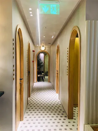 Corridor lined with arched timber doorways and a patterned floor
