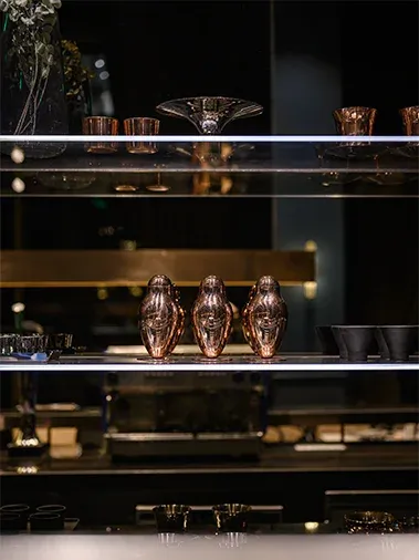 Lit shelves with copper vessels behind the bar