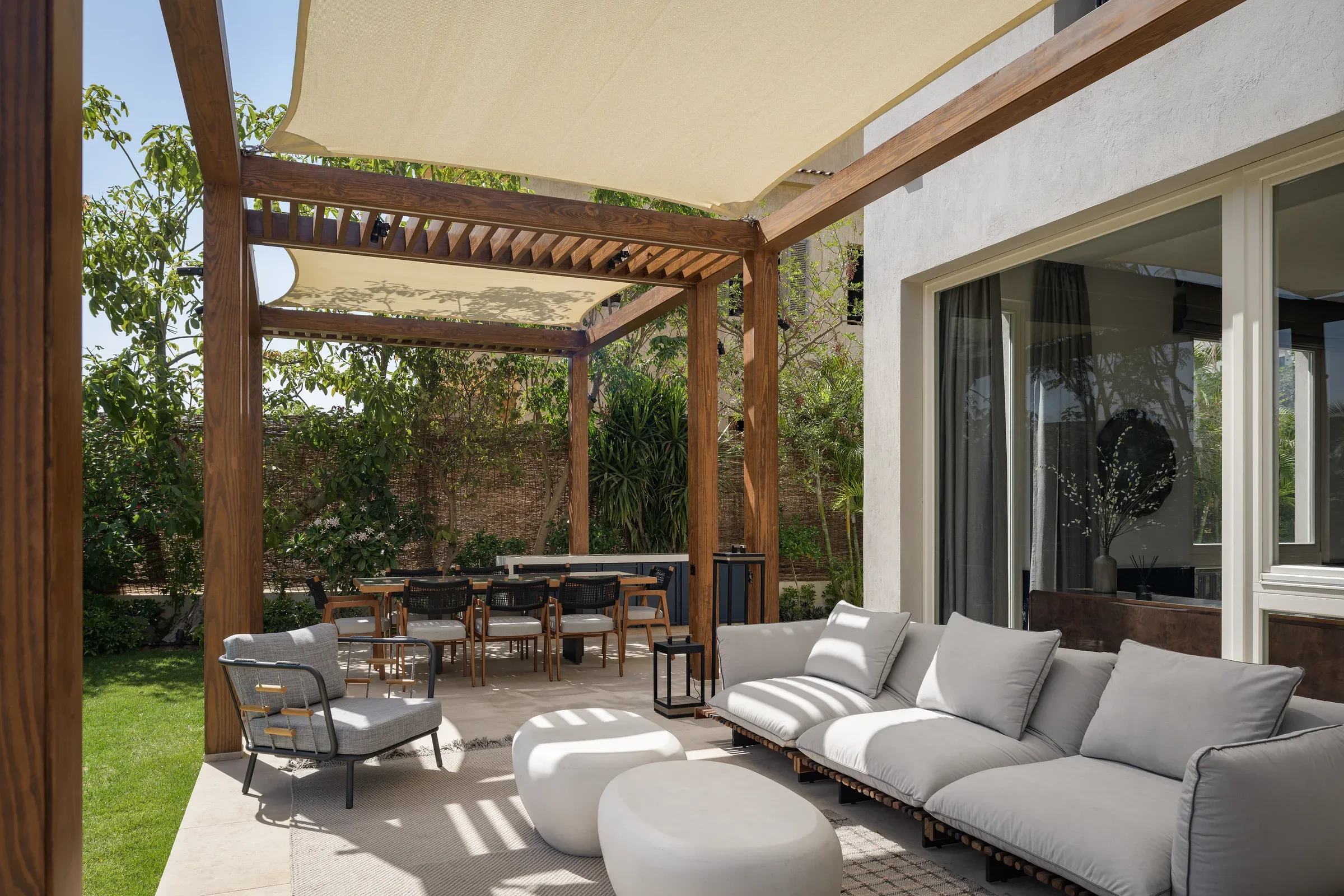 Covered terrace with grey outdoor sofas under a timber pergola
