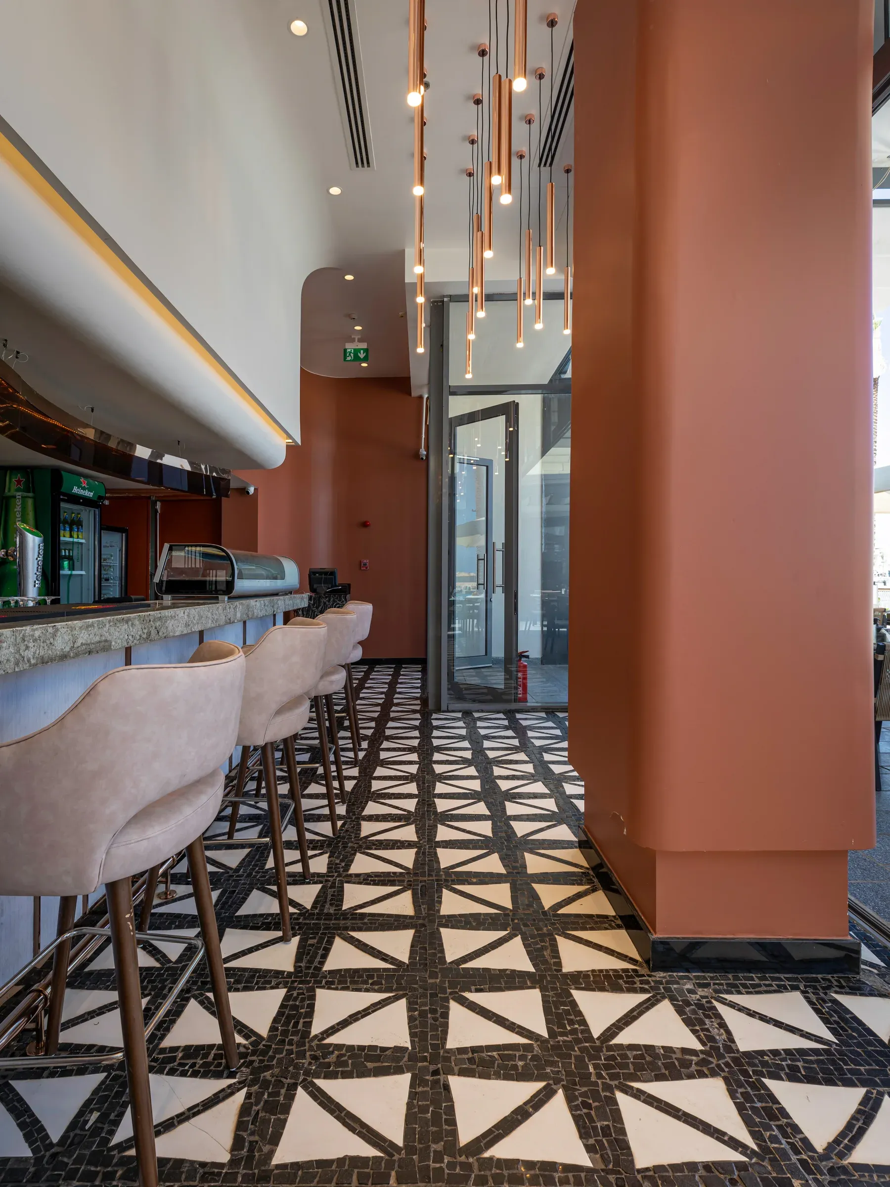 Bar stools and a terracotta column on a black and white tiled floor