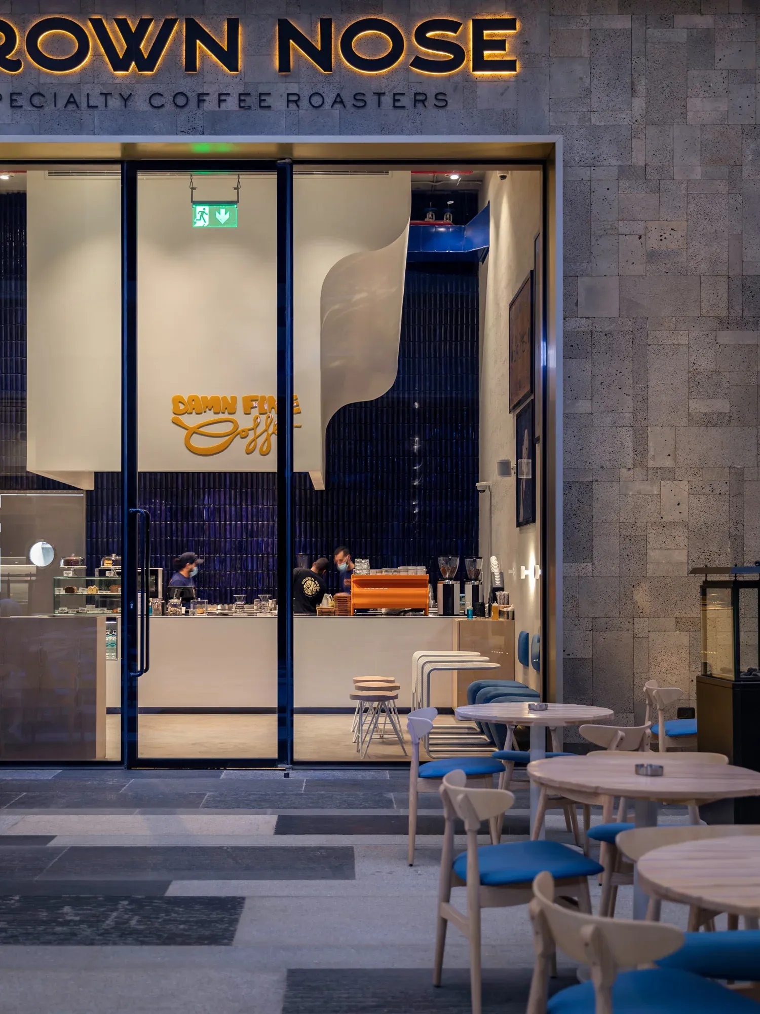 Close view of the storefront sign above blue chairs and round tables